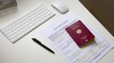 Beyaz ofis masasında Alman pasaportlu bir vize başvuru belgesini kapat
