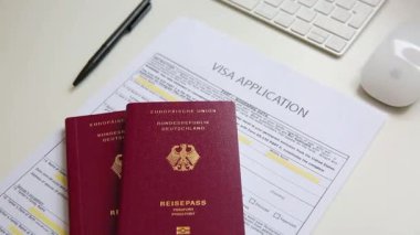 Beyaz ofis masasında iki Alman pasaportlu bir vize başvuru belgesini kapat