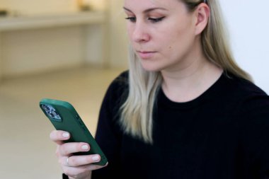 Kanepede otururken akıllı bir telefona odaklanan beyaz bir kadının portresini yakından çek. İnternette sohbet, çalışma ya da öğrenim