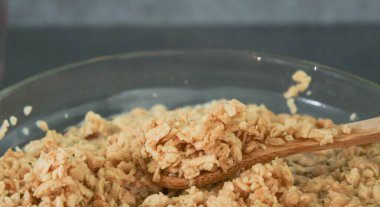 Soya fasulyesi kıymalı kıyma, tahta kaşık ve cam kâse üzerinde, gri mutfak masasında suyun içine çekilir.