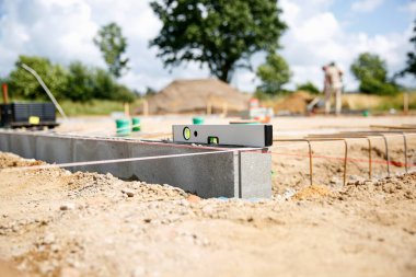 Kesin bir ölçüm için beton taşın üzerinde duran bir ruh seviyesine yaklaş. Ev inşaatı 