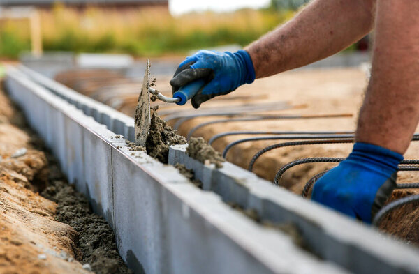 Close up of a bricklayer worker making cement mortar on a wall block, blurred background. Construction site concept 