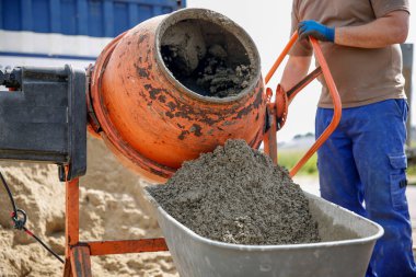 Turuncu bir mikserde beton üreten bir daraltma işçisine yakın çekim