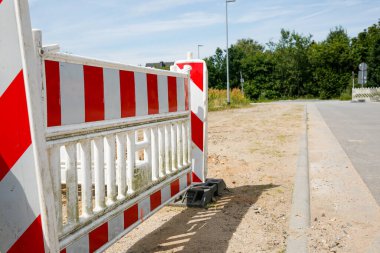 Gün ışığında bir inşaat alanındaki kırmızı ve beyaz bariyeri kapatın. 