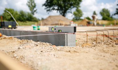 Kesin bir ölçüm için beton taşın üzerinde duran bir ruh seviyesine yaklaş. Ev inşaatı 