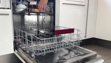 Bulaşık makinesinden temiz bulaşık çıkaran bir kadının fotoğrafını çek. 