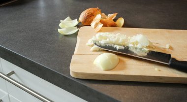 Tahta bir tahtanın üzerinde kesilmiş beyaz soğanı bıçakla kapat, koyu gri mutfak masası. 