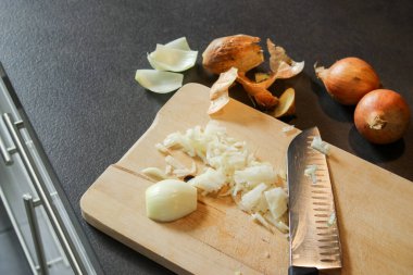 Tahta bir tahtanın üzerinde kesilmiş beyaz soğanı bıçakla kapat, koyu gri mutfak masası. 