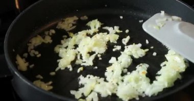 Siyah bir tavada kızartılmış çiğ soğan, soğan ve yağ spreyli gri mutfak masası.