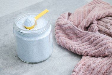 Çamaşır deterjanı ve gri masanın üstünde kirli pembe bir havlu. Kumaş leke çıkarıcı kavramı