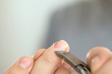 Cımbızla tırnaklarını kesen kadın manikürü.