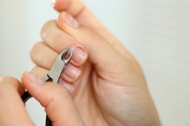 Cımbızla tırnaklarını kesen kadın manikürü.