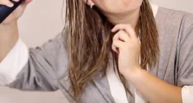 Sarışın saçlarını evde kurutan bir kadına yakın çekim. Ev konseptinde sağlıklı saç ve saç bakımı 