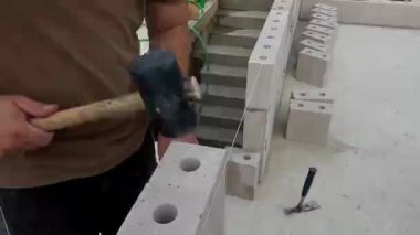 İnşaat işçisi bir duvarcının plastik çekiç beyaz taş ile kapıyı çalması, duvar inşa etmesi. Çekirdek ve kabuk inşa kavramı 