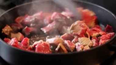 Siyah tavada elektrikli sobanın üstünde kızaran sığır etini yakın, arka plan bulanık. 