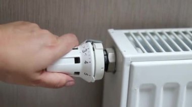 Termostat radyatörünü en yüksek pozisyonda çeviren bir kadın eli. Soğuk mevsim konseptinde evleri ısıtmak. Yüksek kaliteli FullHD görüntüler