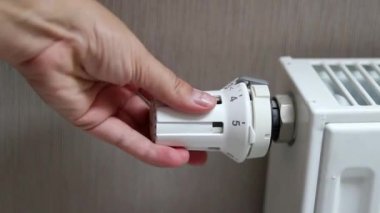 Orta pozisyondaki termostat radyatörünü çeviren bir kadın eli. Soğuk mevsim konseptinde evleri ısıtmak. Yüksek kaliteli FullHD görüntüler