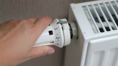 Orta pozisyondaki termostat radyatörünü çeviren bir kadın eli. Soğuk mevsim konseptinde evleri ısıtmak. Yüksek kaliteli FullHD görüntüler