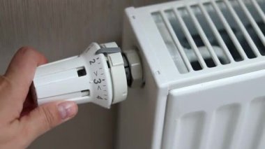 Orta pozisyondaki termostat radyatörünü çeviren bir kadın eli. Soğuk mevsim konseptinde evleri ısıtmak. Yüksek kaliteli FullHD görüntüler