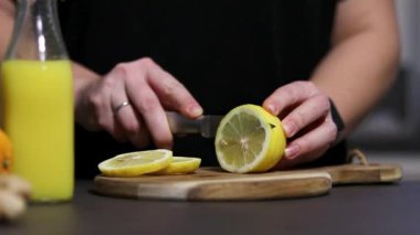 Mutfakta ev yapımı limon ve zencefilli içecek için limon kesen bir kadının görüntüsü bulanık. Soğuk baca ve bağışıklık güçlendirici konsept. Yüksek kaliteli FullHD görüntüler