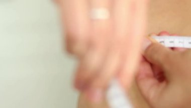 Karnını bant ile ölçen bir kadının yakın çekimi. Şişman, göbekli tiplerden. Sağlıksız yaşam tarzı diyet konsepti. Yüksek kaliteli FullHD görüntüler