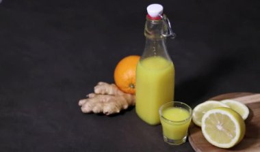 Ev yapımı portakal, limon ve zencefilli içecek. Mutfak masasında küçük bardakta, arka planda bulanık. Soğuk baca ve bağışıklık güçlendirici konsept. Yüksek kaliteli FullHD görüntüler