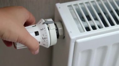 Termostat radyatörünü en soğuk pozisyonda çeviren bir kadın eli. Soğuk mevsim konseptinde evleri ısıtmak. Yüksek kaliteli FullHD görüntüler