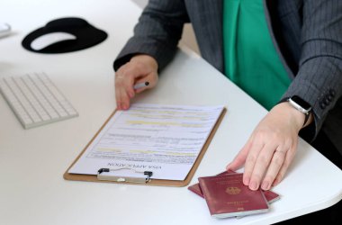 Kafkas bir kadının ofis masasında Alman pasaportu ile vize başvuru formlarını doldurmasının en iyi görüntüsü.