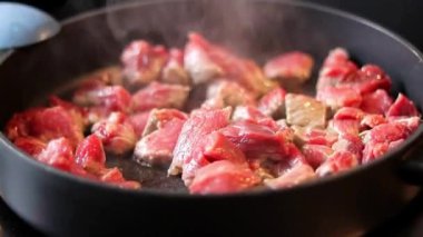 Siyah tavada elektrikli sobanın üstünde kızaran sığır etini yakın, arka plan bulanık. 