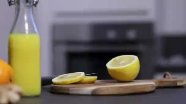Ev yapımı portakal, limon ve zencefilli içecek. Mutfak masasında küçük bardakta, arka planda bulanık. Soğuk baca ve bağışıklık güçlendirici konsept. Yüksek kaliteli FullHD görüntüler