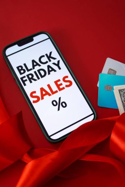Kara Cuma online satışını kredi kartları ve parayla kırmızı arka planda gösteren bir akıllı telefon ekranının üst görüntüsü. Metin için boş kopyalama alanı