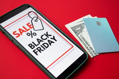 Kara Cuma online satışını kredi kartları ve nakit parayla kırmızı arka planda gösteren bir akıllı telefon ekranını kapat