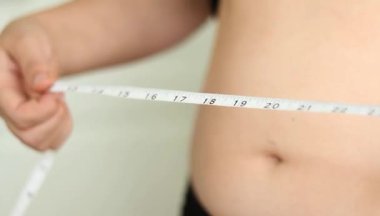 Karnını bant ile ölçen bir kadının yakın çekimi. Şişman, göbekli tiplerden. Sağlıksız yaşam tarzı diyet konsepti. Yüksek kaliteli FullHD görüntüler