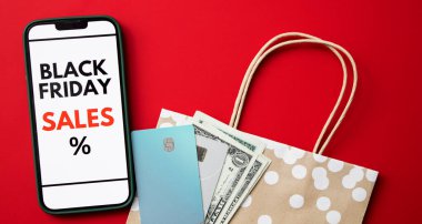 Kara Cuma online satışını kredi kartları, nakit para ve bir alışveriş çantası ile kırmızı arka planda gösteren akıllı telefon ekranının üst görüntüsünü kapat