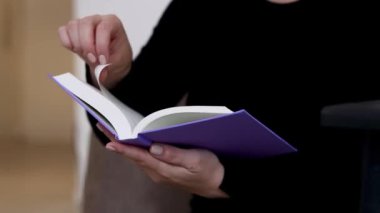 Kafkasyalı bir kadının kanepede oturduğu ve mor bir maket kitap okuduğu, arka planda bulanıklık olan 