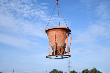 İnşaat alanında beton kovalı bir vinç, zemini betonla dolduruyor. .