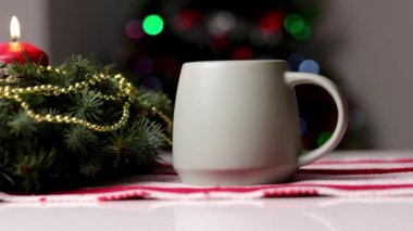 Beyaz masada kırmızı mumlar ve çelenklerle dolu sıcak bir bardak. Konforlu ev dekorasyonu 