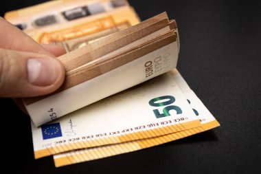 Siyah masa arkaplanındaki 50 avroluk banknotları sayan bir kadına yaklaş.