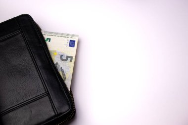 Siyah deri cüzdan ve beyaz masa arkasında beş euro banknotlar.