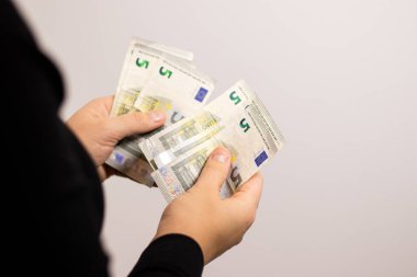 Beş avroluk banknotlar sayan bir kadına yaklaş. Fotokopi alanı olan gri bir arka plan. 