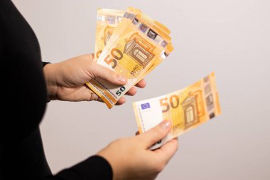 50 avroluk banknotlar sayan bir kadının yakın plan fotoğrafı. Fotokopi alanı olan gri arka plan.