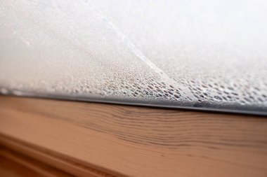 Soğuk mevsimde bir evin penceresindeki buharlaşmayı kapat, su damlaları ve nem oranı, bulanık arka plan.