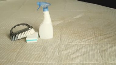 Süngerli bir sprey şişesi ve sarı lekeli kirli bir yatağın üzerinde fırça. Ev konseptinde tekstil temizliği. Yüksek kaliteli FullHD görüntüler