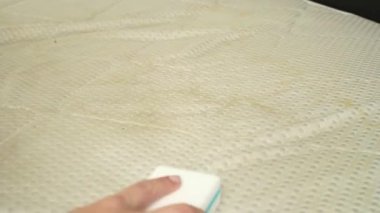 Kirli bir yatağı sarı lekelerle temizleyen bir kadına yaklaş. Ev konseptinde tekstil temizliği. Yüksek kaliteli FullHD görüntüler