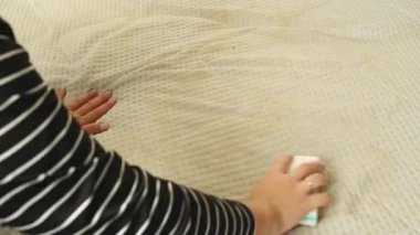 Kirli bir yatağı sarı lekelerle temizleyen bir kadına yaklaş. Ev konseptinde tekstil temizliği. Yüksek kaliteli FullHD görüntüler