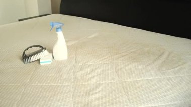 Süngerli bir sprey şişesi ve sarı lekeli kirli bir yatağın üzerinde fırça. Ev konseptinde tekstil temizliği. Yüksek kaliteli FullHD görüntüler