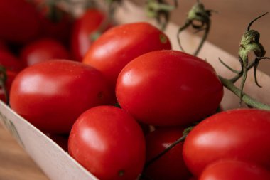 Mutfak masasındaki eko karton kutuda organik kırmızı kiraz domateslerini kapatın.