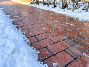 Kışın kar ve kumla kaplı buzlu bir yaya kaldırımı yol kavramında tuz önleyici kimyasallar.