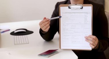 Ofis masasında Alman pasaportu olan beyaz bir kadının vize başvuru formlarını doldurması. Yüksek kaliteli FullHD görüntüler