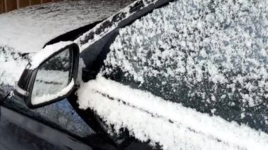 Kışın karla kaplı siyah bir arabanın yan aynasına yaklaş. 